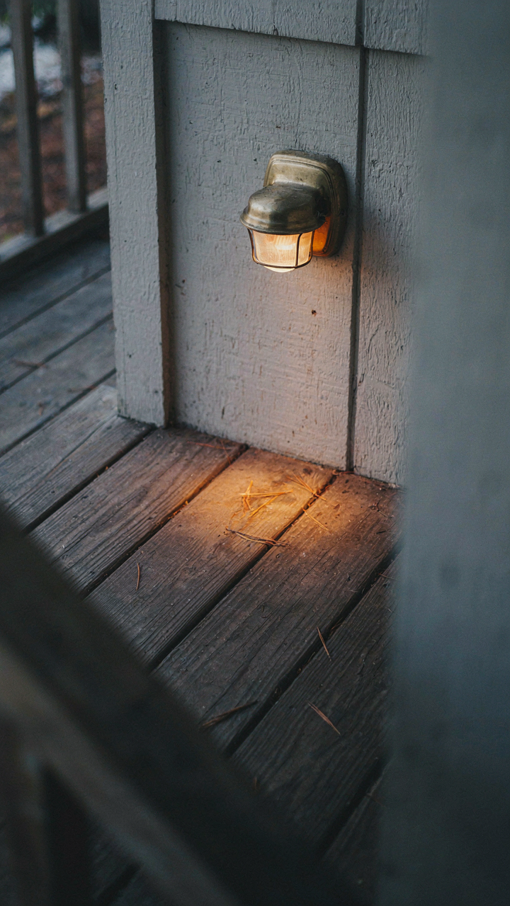 A small wall light casts a warm, focused glow on a porch corner.