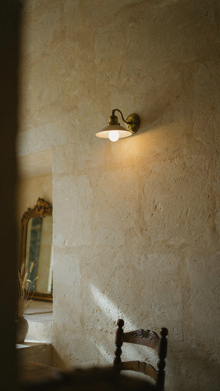 A classic wall sconce casts a soft glow on a textured wall.