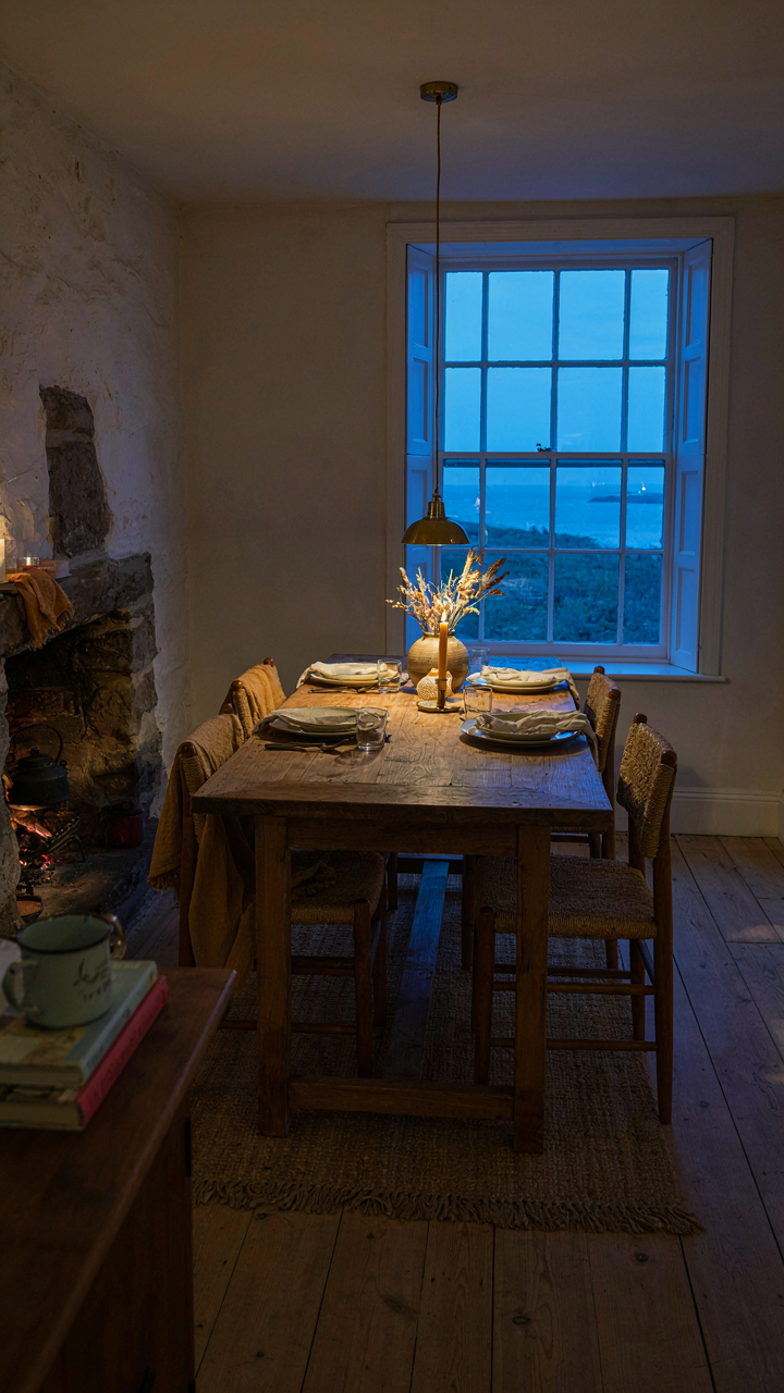 A coastal dining room at dusk with soft, layered lighting.