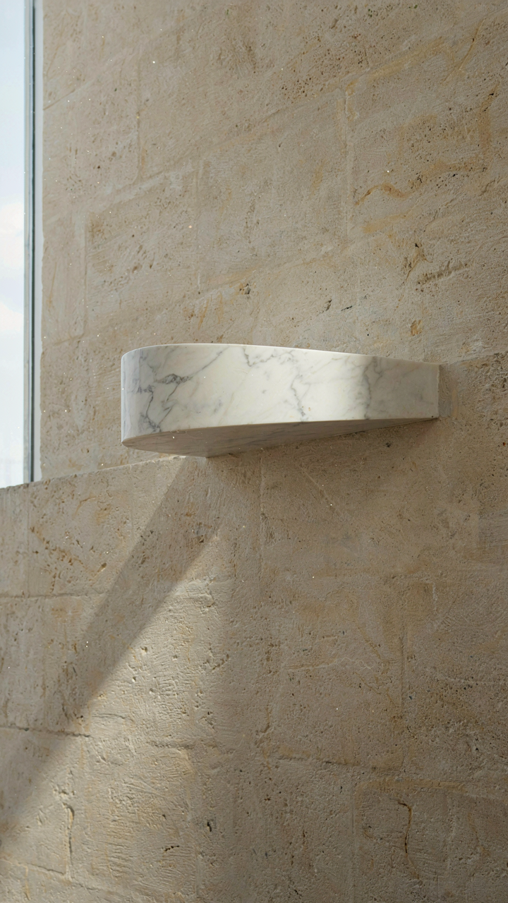 A single cantilevered marble stair tread anchored into a stone wall.