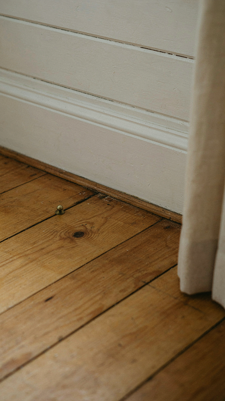 Close-up of wide-plank pine flooring and whitewashed shiplap.