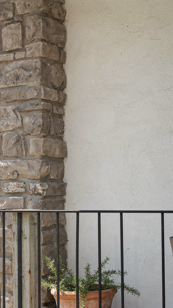 Rough stone and weathered wood materials contrasting on a ranch house porch.