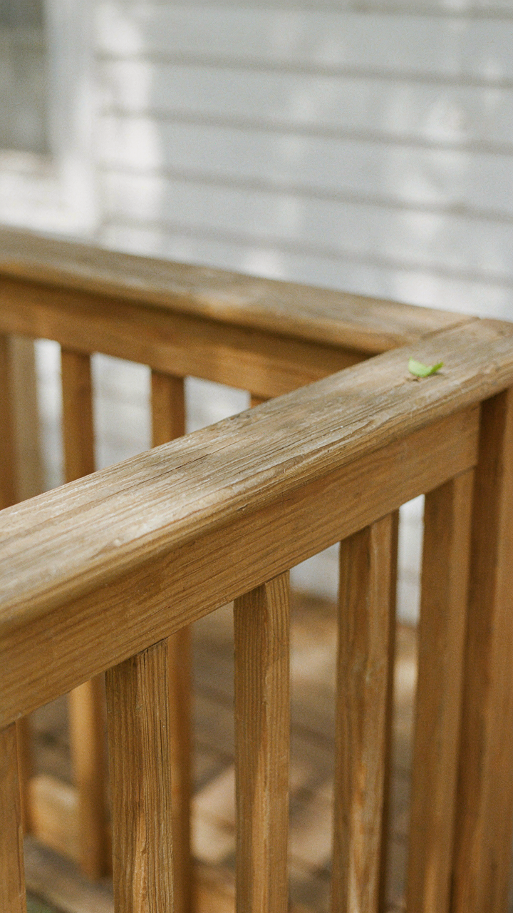 A close-up view of durable cedar wood railings on a small house with wraparound porch.