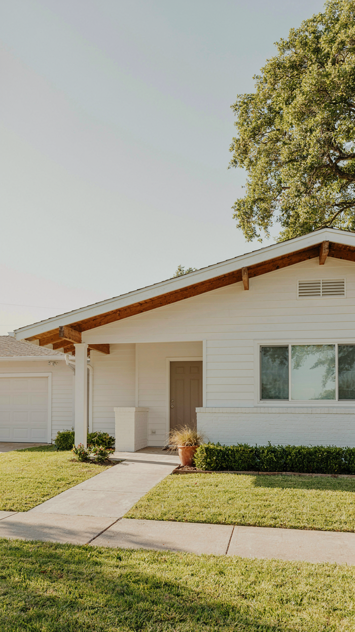 A mid century ranch exterior showing wide roof overhangs and exposed rafter tails.