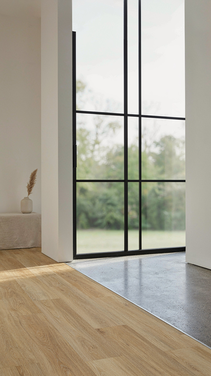 Luxury vinyl plank flooring meets a polished concrete slab next to a sliding glass door.