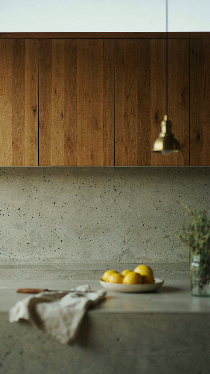 A concrete countertop with visible use marks sits in a modern cabin kitchen against wood panels.