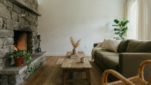 A modern rustic living room with a stone fireplace and an olive green sofa.