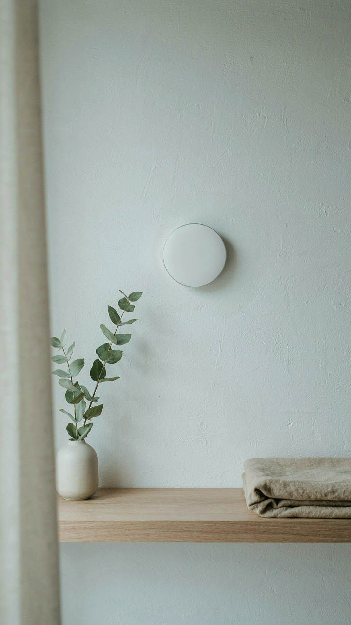 A sleek smart thermostat on a white wall in a scandinavian tiny house.