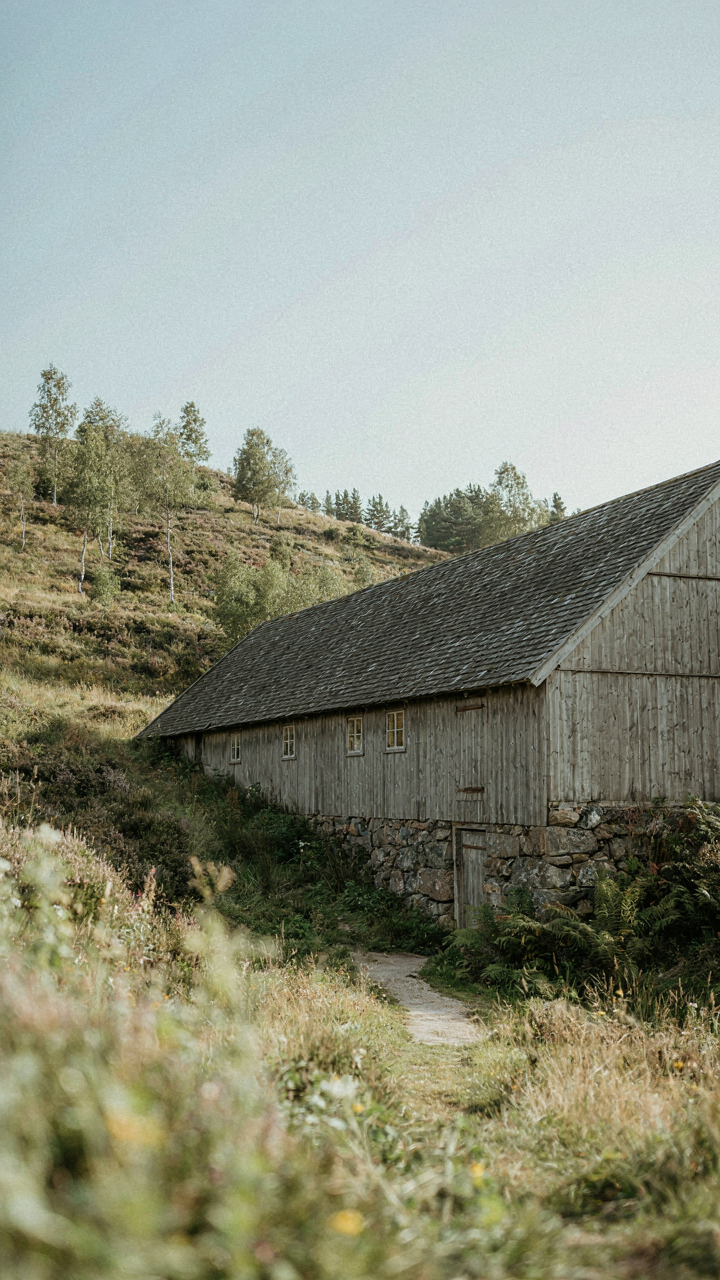 Scandinavian barn house integrated into a sloping hillside with a stone foundation.