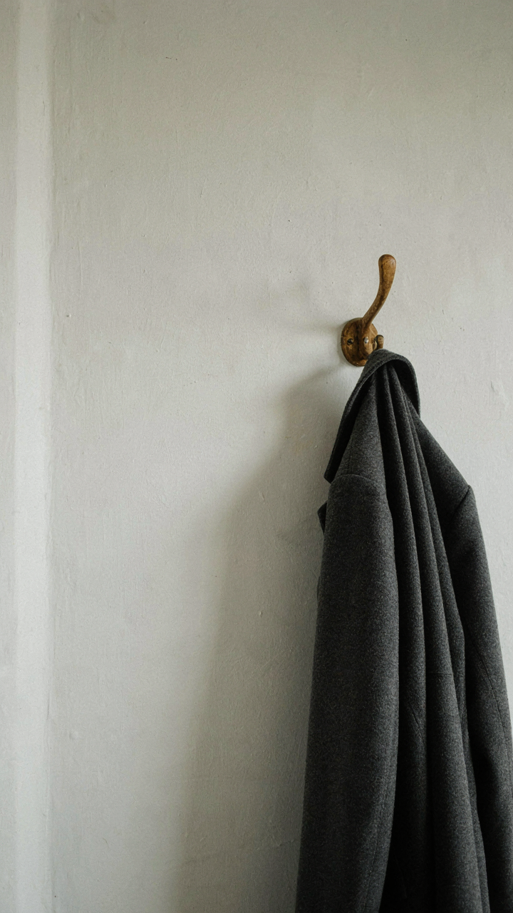 A single wooden hook on a wall holding one coat, showing limited storage.