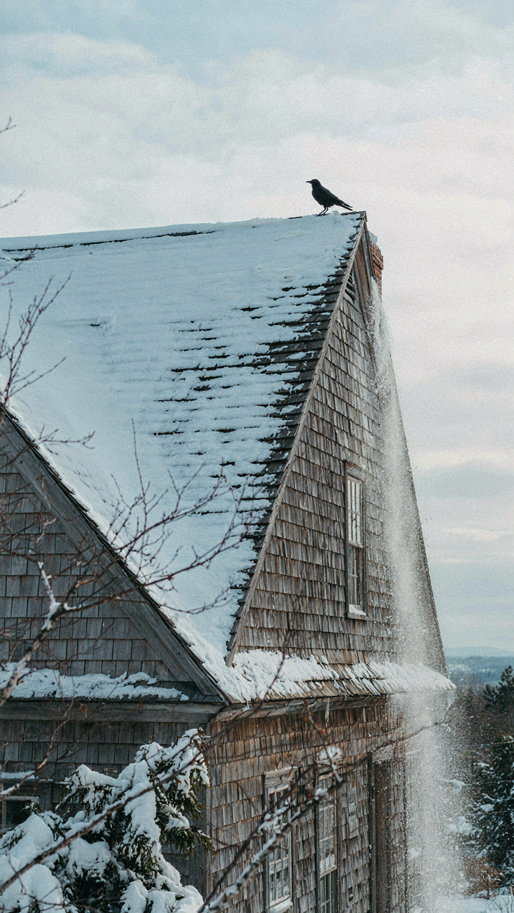 A steep-pitched colonial farmhouse roof shedding heavy snow.