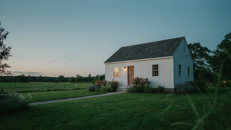 A charming one story cottage plan with a welcoming glow at sunrise.