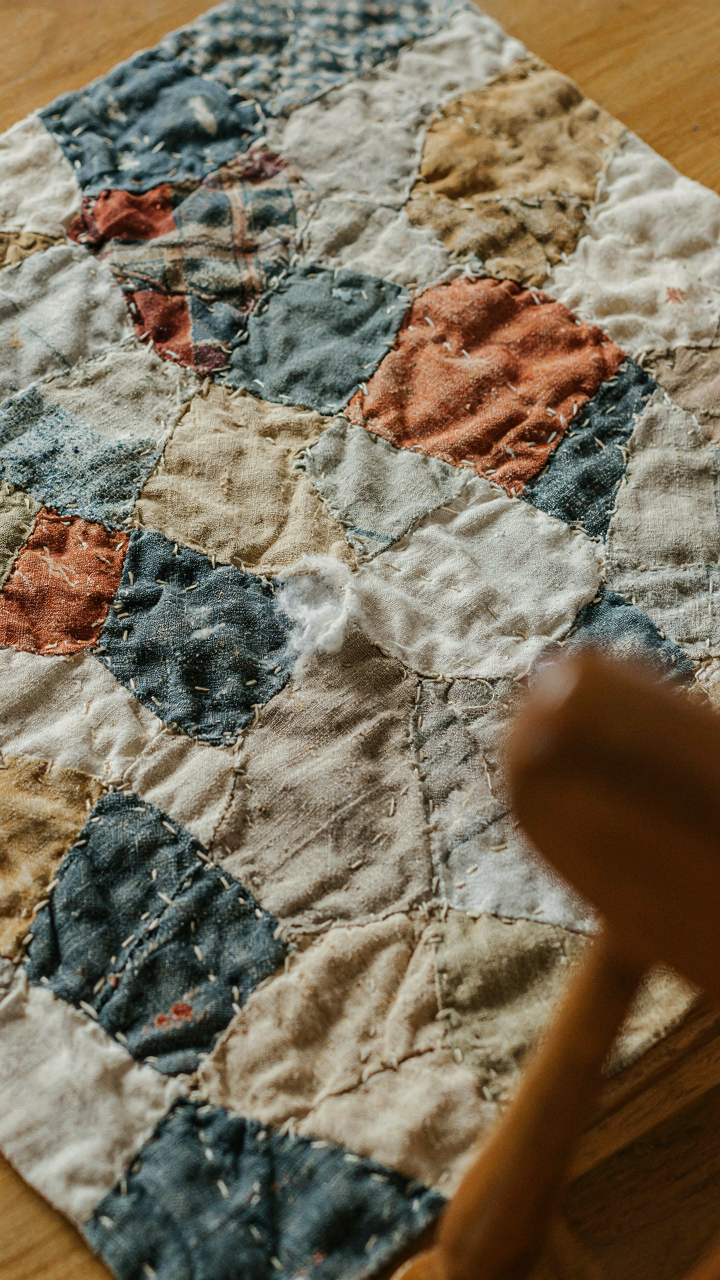 A close up of a hand-stitched quilt showing uneven stitches and cotton batting.