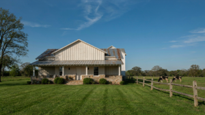 A modern ranch farmhouse with natural stone and wood siding, a low-slung roof, and deep eaves.