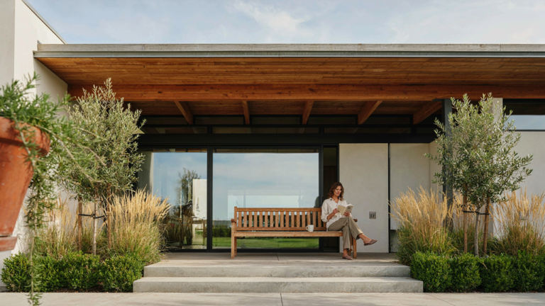 A wide view of a modern ranch house porch with deep overhang and comfortable seating.