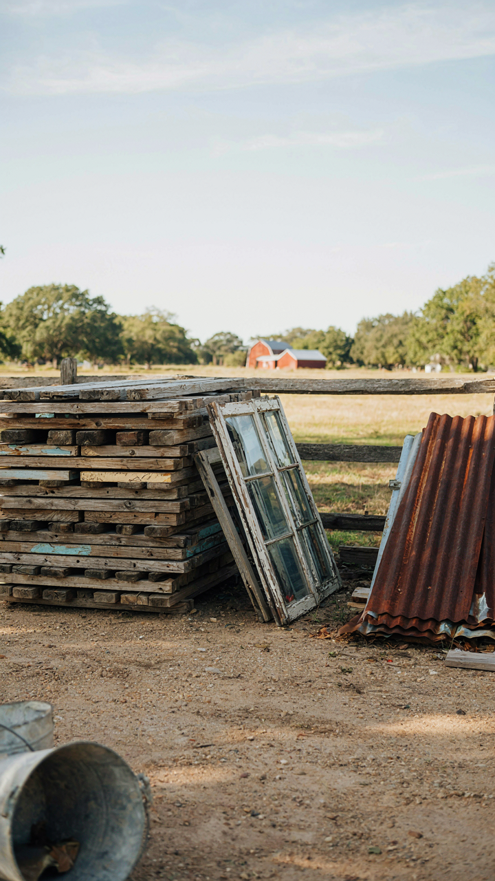 Various reclaimed building materials, like wood and tin, stacked in a yard.