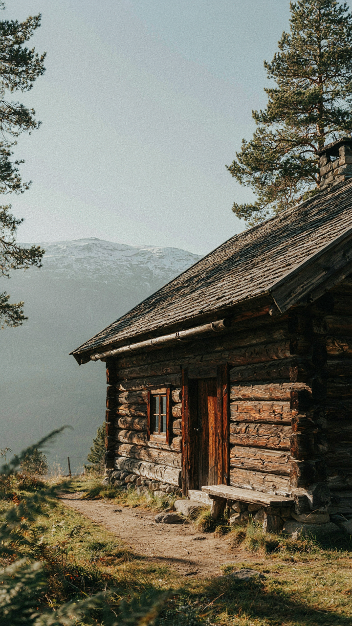 An old, solid log Norwegian cabin with wide eaves and a steep roof.