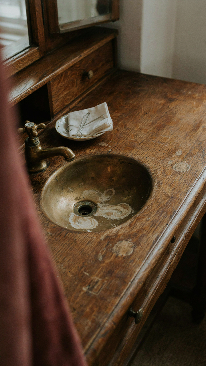 A close up of an antique wooden vanity with real water stains and worn hardware.