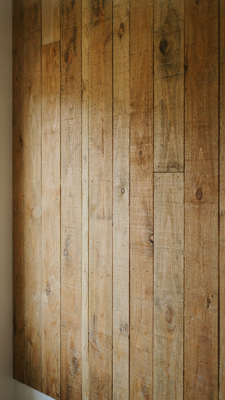 Close up of a rustic farmhouse shiplap accent wall with visible knots and uneven stain.