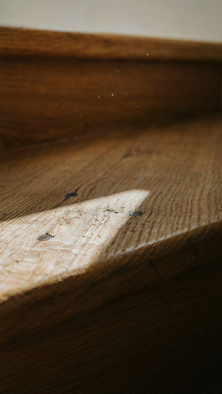 A close-up of a hand-planed wooden stair tread showing texture and knots.