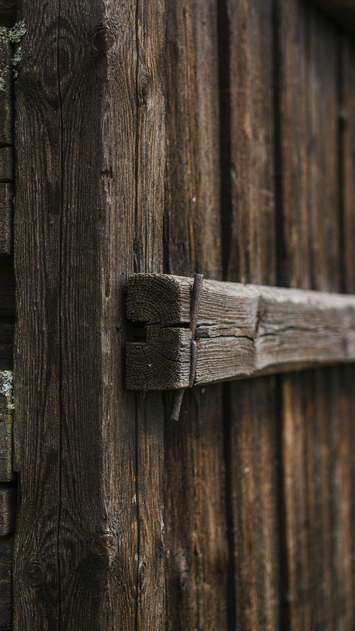 A close-up of dark, weathered heavy timber frame with visible joinery.