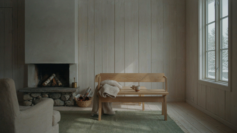 A warm and inviting Scandinavian cabin interior features pale wood walls and a scenic window view.