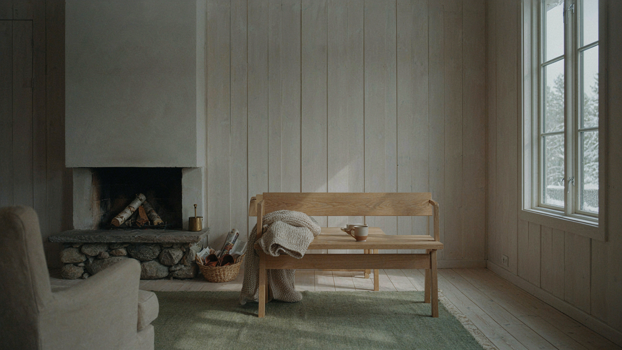 A warm and inviting Scandinavian cabin interior features pale wood walls and a scenic window view.