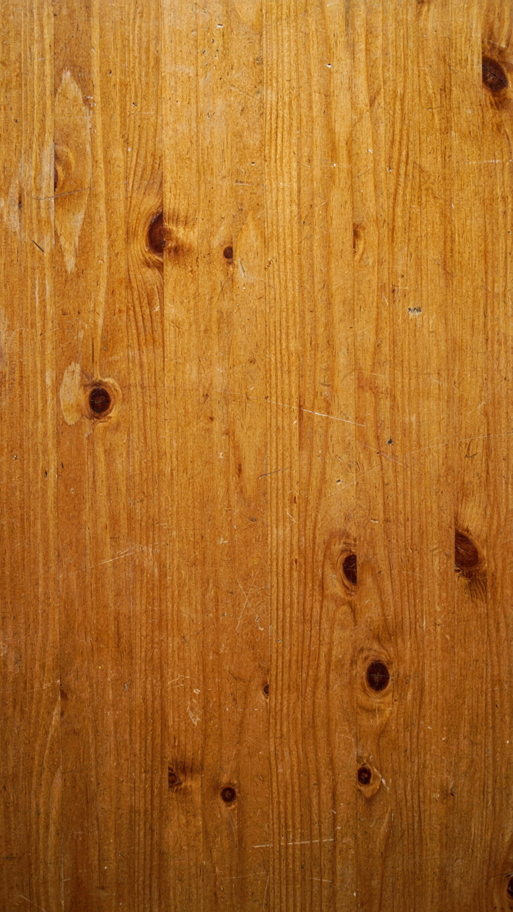 Close-up of a raw pine table surface with visible patina and light scratches.