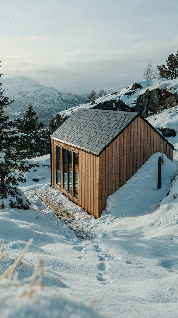 A small Scandinavian tiny house stands in a snowy Norwegian landscape.