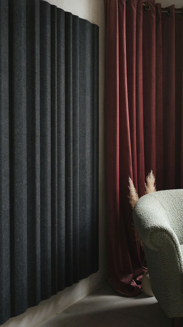 An acoustic panel on a wall, a heavy curtain, and an upholstered armchair.