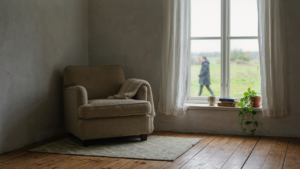 A warm and inviting small farmhouse interior with a cozy armchair by a sunlit window.