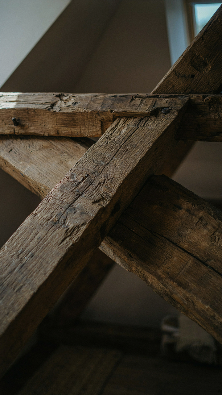 Reclaimed timber beams show strong joinery in a rustic tiny cottage loft.