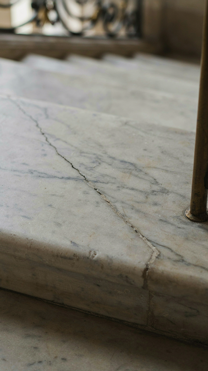 A hairline crack runs across a marble tread on a grand chateau staircase.