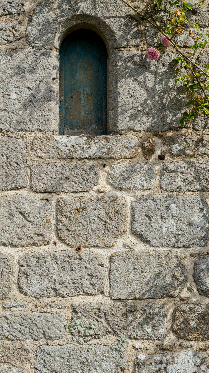 A granite wall on a centuries-old French cottage with visible lime mortar.