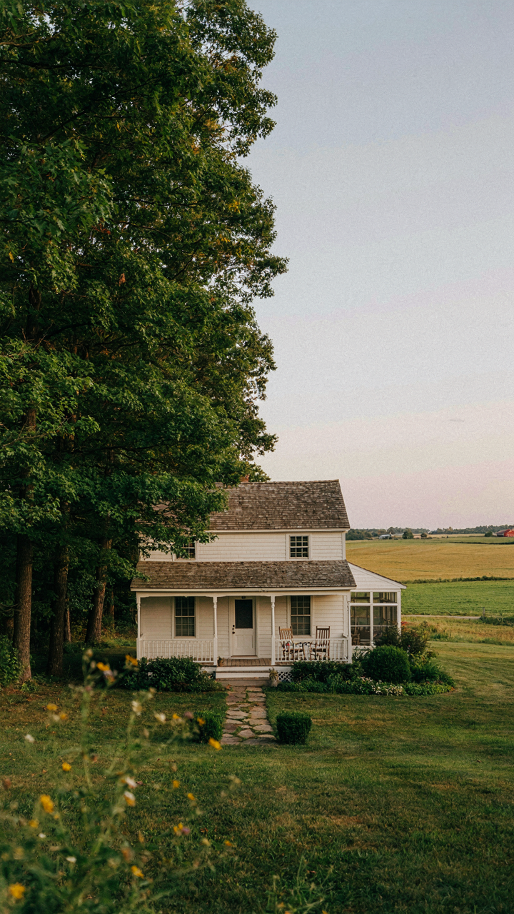 Tall trees provide privacy to a farmhouse wraparound porch, while other sides offer open views.