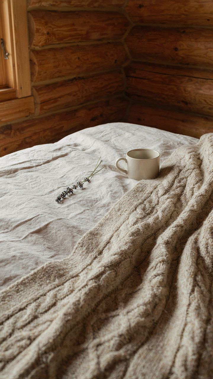 Close up of wool and linen bedding on a bed in a log cabin bedroom.