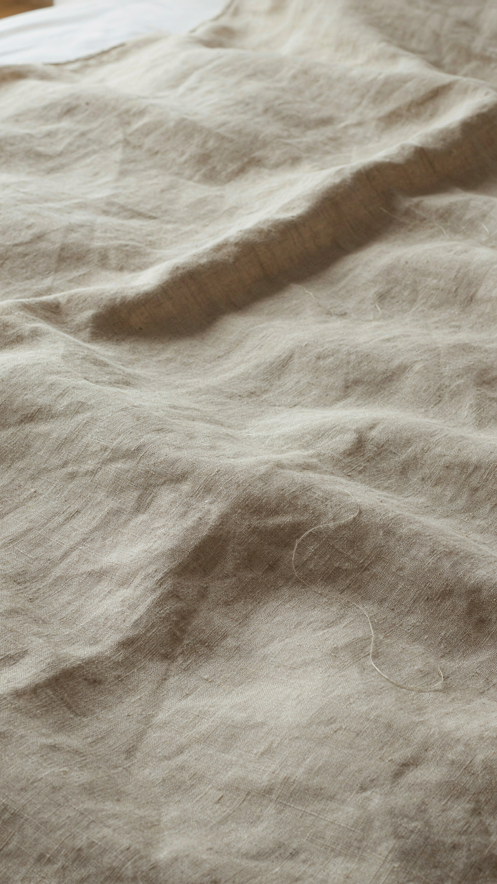 A close up of a textured natural linen duvet cover in a coastal bedroom.