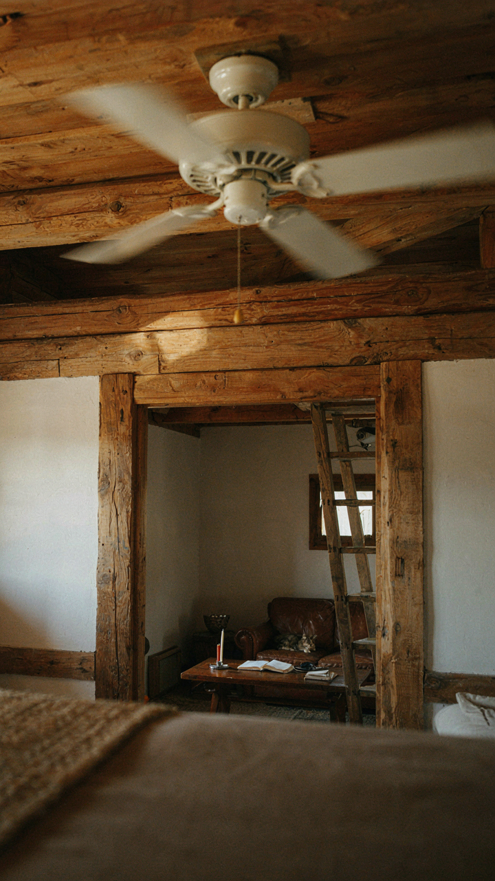A ceiling fan slowly turning in reverse mode in a tiny cabin loft.
