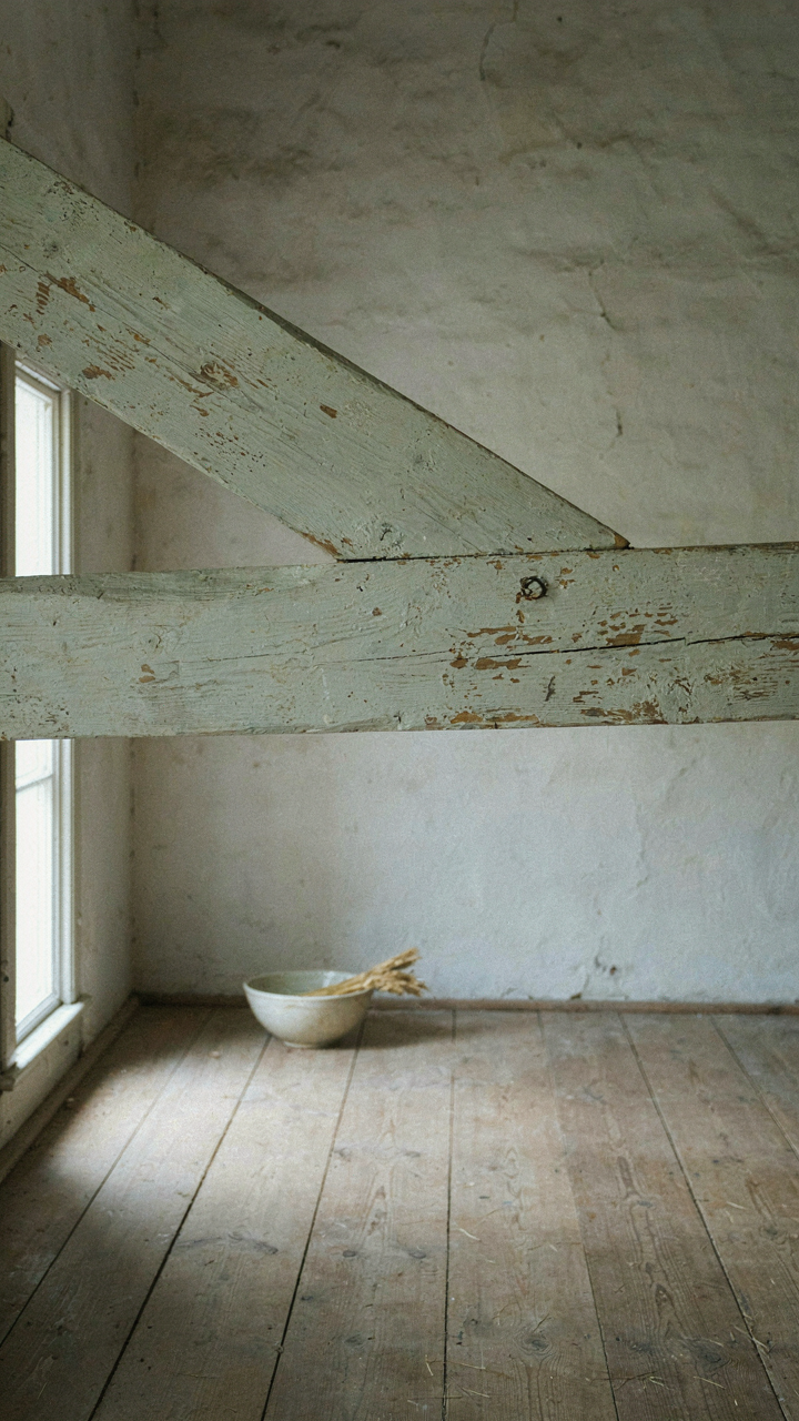 A simple, pale painted wooden beam in an old farmhouse interior.