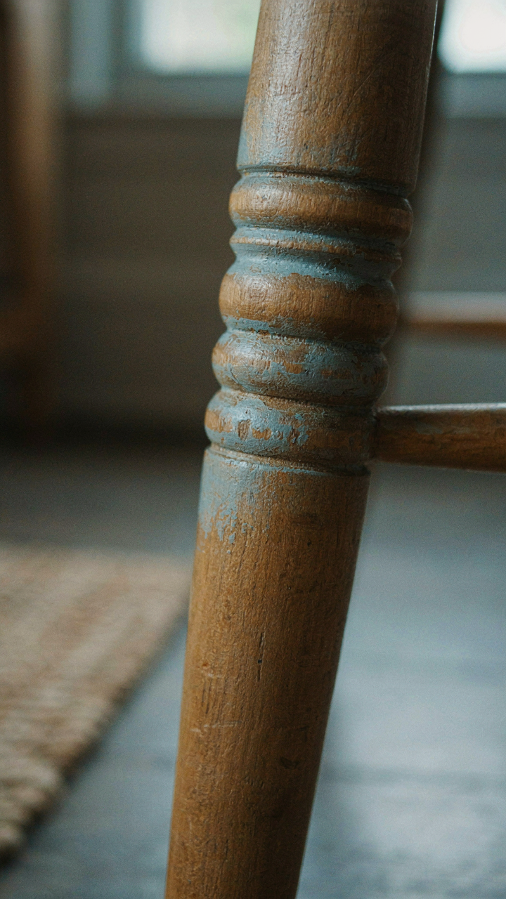A close-up of an old wooden chair leg showing natural wear and authentic patina.