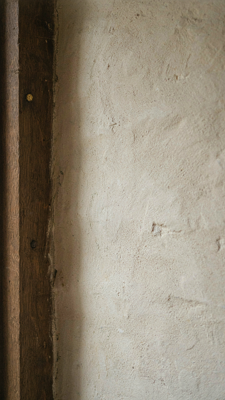 A dark oak beam connects with a textured plaster wall in a Tudor room.