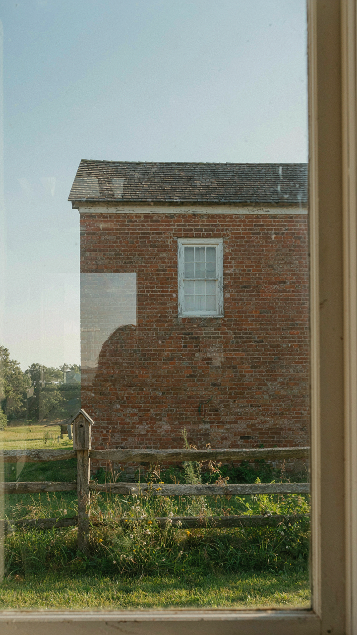 A farmhouse exterior with brick and wood, showing a mismatched cool-gray interior.