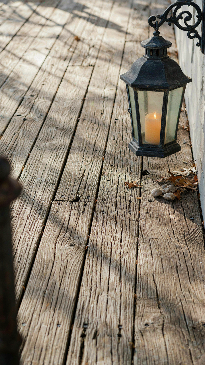 Close-up of weathered wooden porch flooring with a sturdy metal lantern.