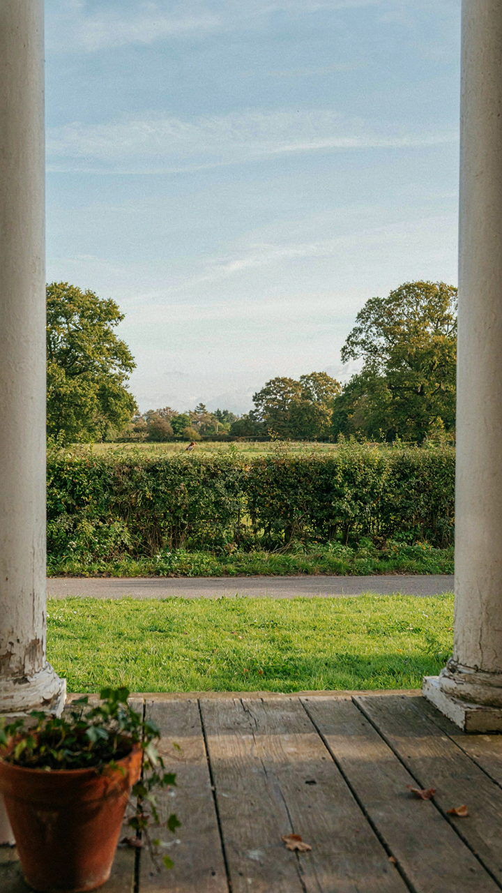 A porch view shows a natural landscape framed by trees and fields.
