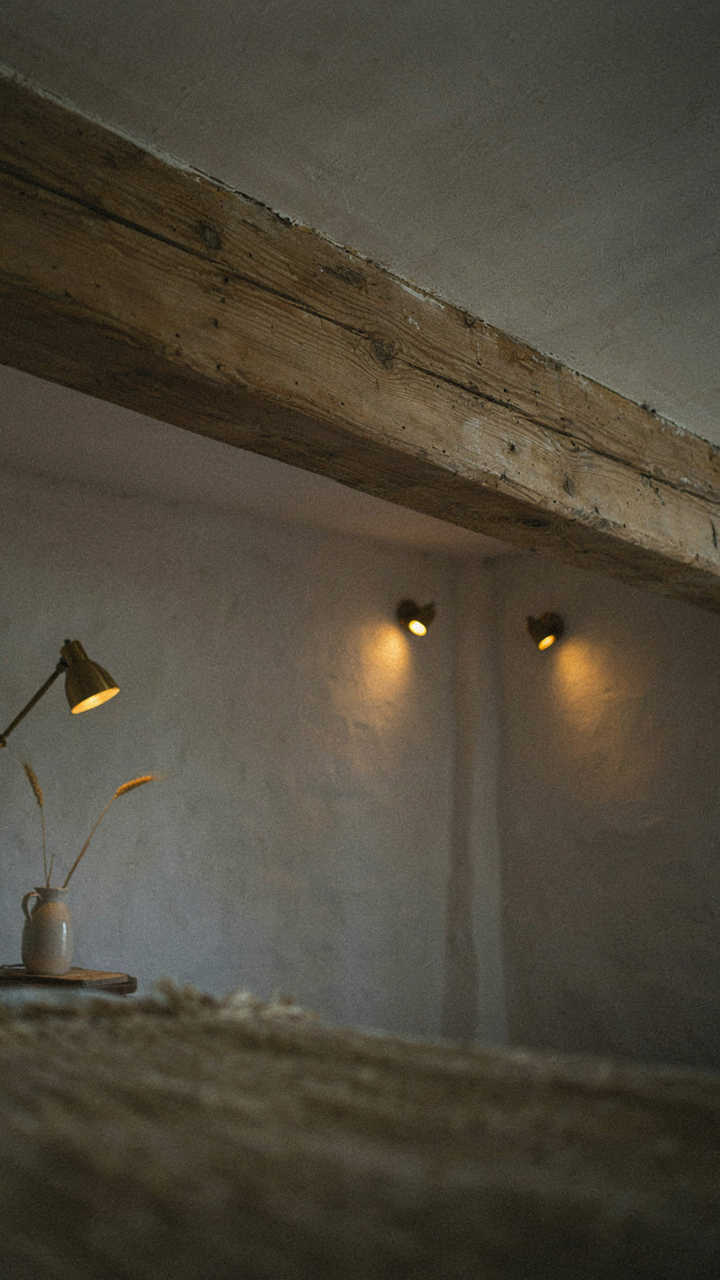 A raw wooden beam in a small farmhouse with warm, layered lighting.
