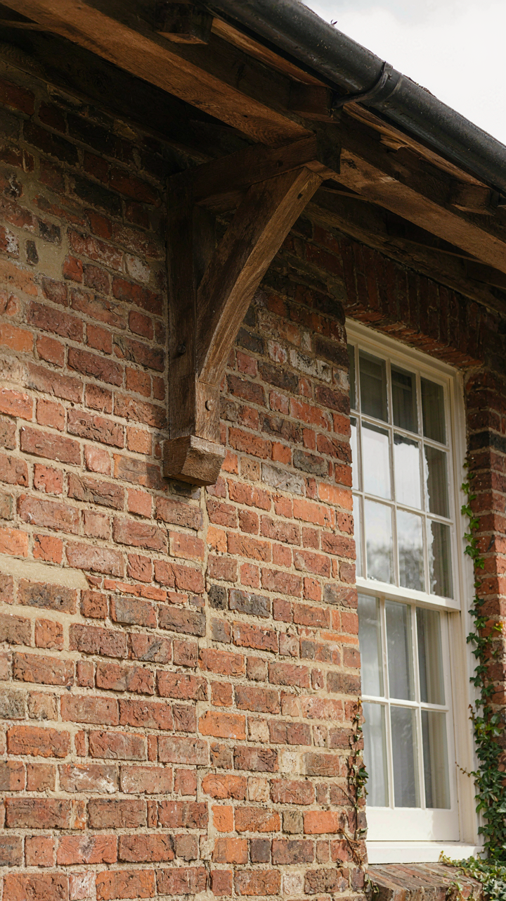 Close-up of a craftsman bungalow's exposed rafter tails and brick foundation.