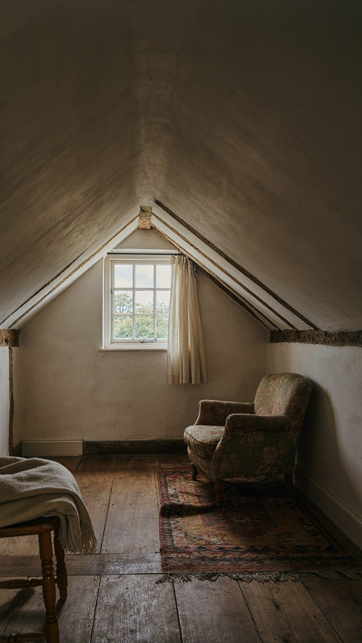 An attic room with a dormer window and sloped ceilings creating limited usable space.
