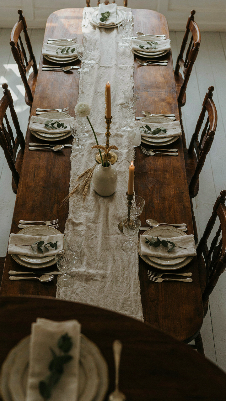 A narrow, long dark wood dining table with antique chairs set close.