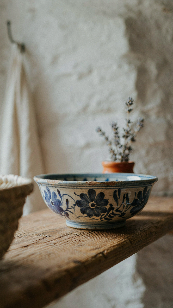 A vintage Quimper pottery bowl on a wooden shelf in a rustic French cottage.