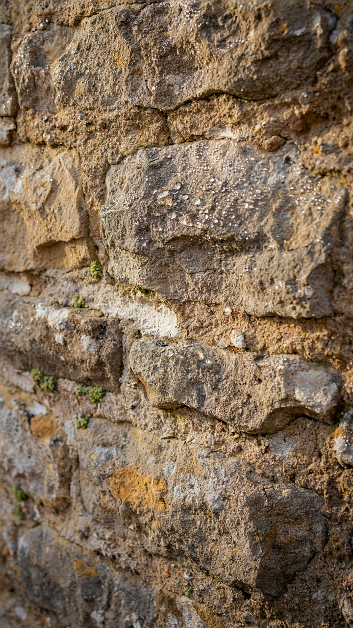 A close-up of an old stone wall with visible lime mortar joints.